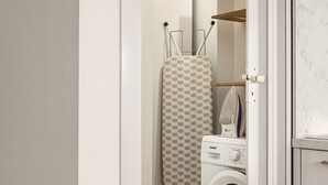 A laundry area with a washing machine, an iron, and an ironing board.