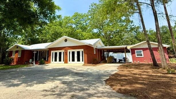 A two-story brick house with a covered porch, a garage, and a small shed. - Charming, convenient, & affordable house near Flint. Sleeps 12 comfortably! (Bainbridge)