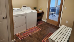 A laundry room with a washer and dryer, a bench, and a door leading to an outdoor area. - Charming, convenient, & affordable house near Flint. Sleeps 12 comfortably! (Bainbridge)