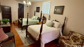 A bedroom with a four-poster bed, a chair, a table, and a window with blinds. - Charming, convenient, & affordable house near Flint. Sleeps 12 comfortably! (Bainbridge)