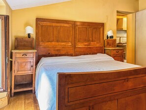 A bedroom with a wooden bed, a nightstand, a dresser, and a mirror.