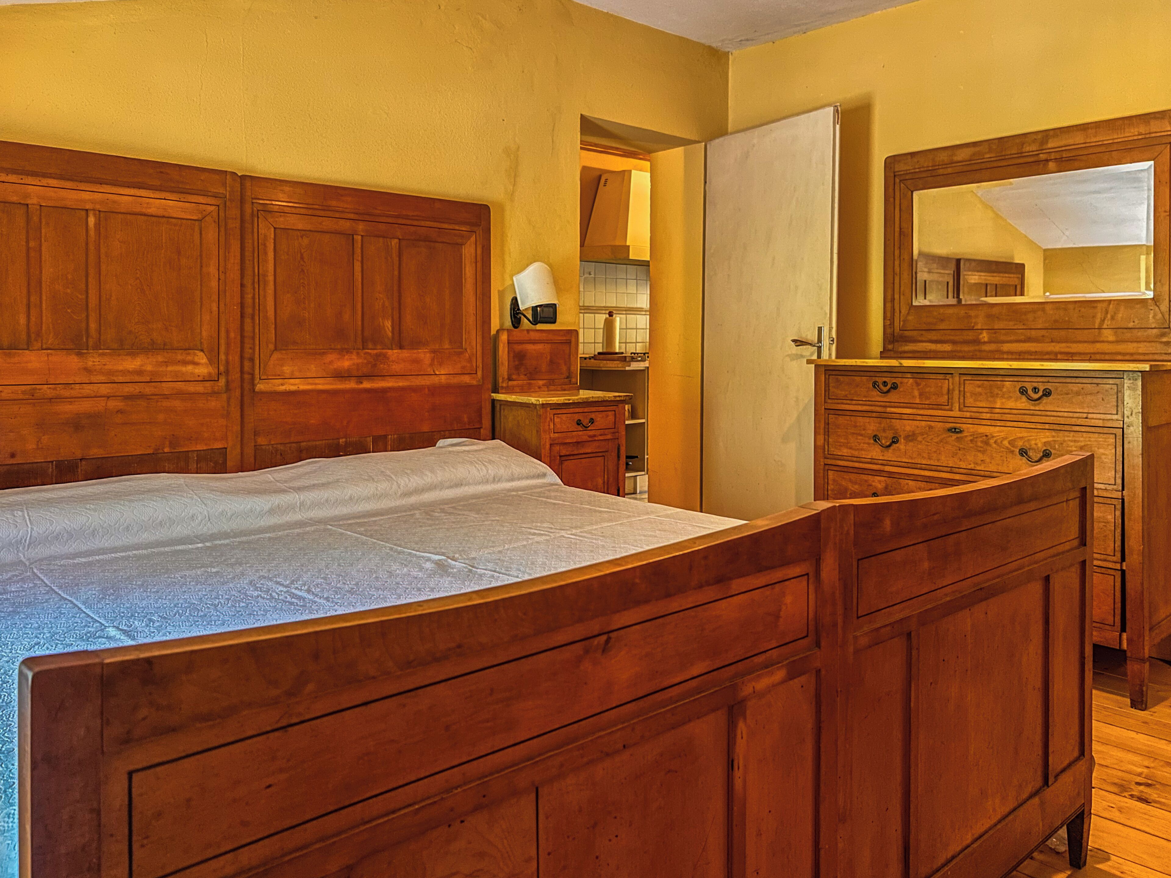 Un dormitorio con cama de madera, cómoda y espejo.