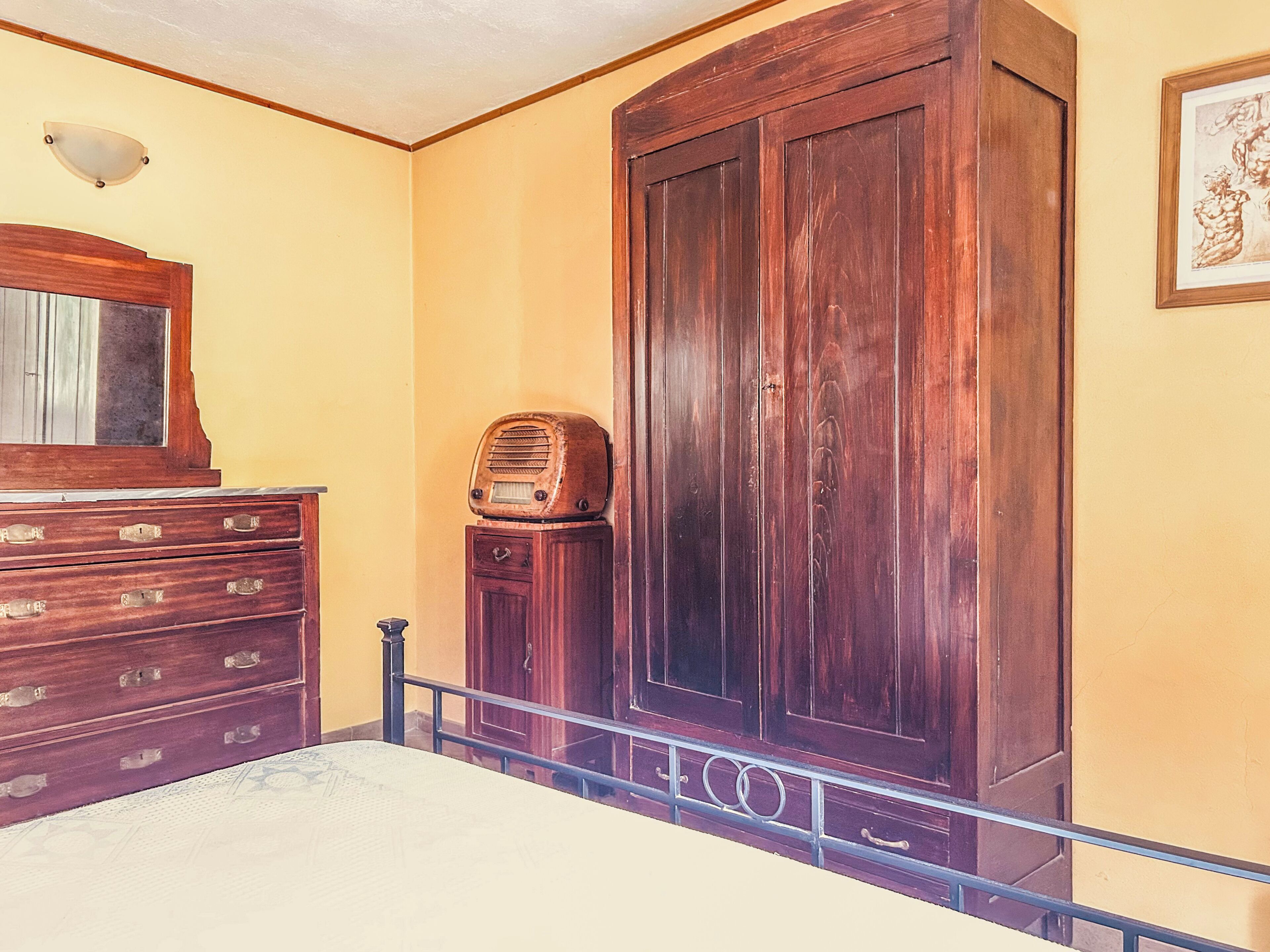 A room with a bed, wooden dresser, and a large wardrobe.