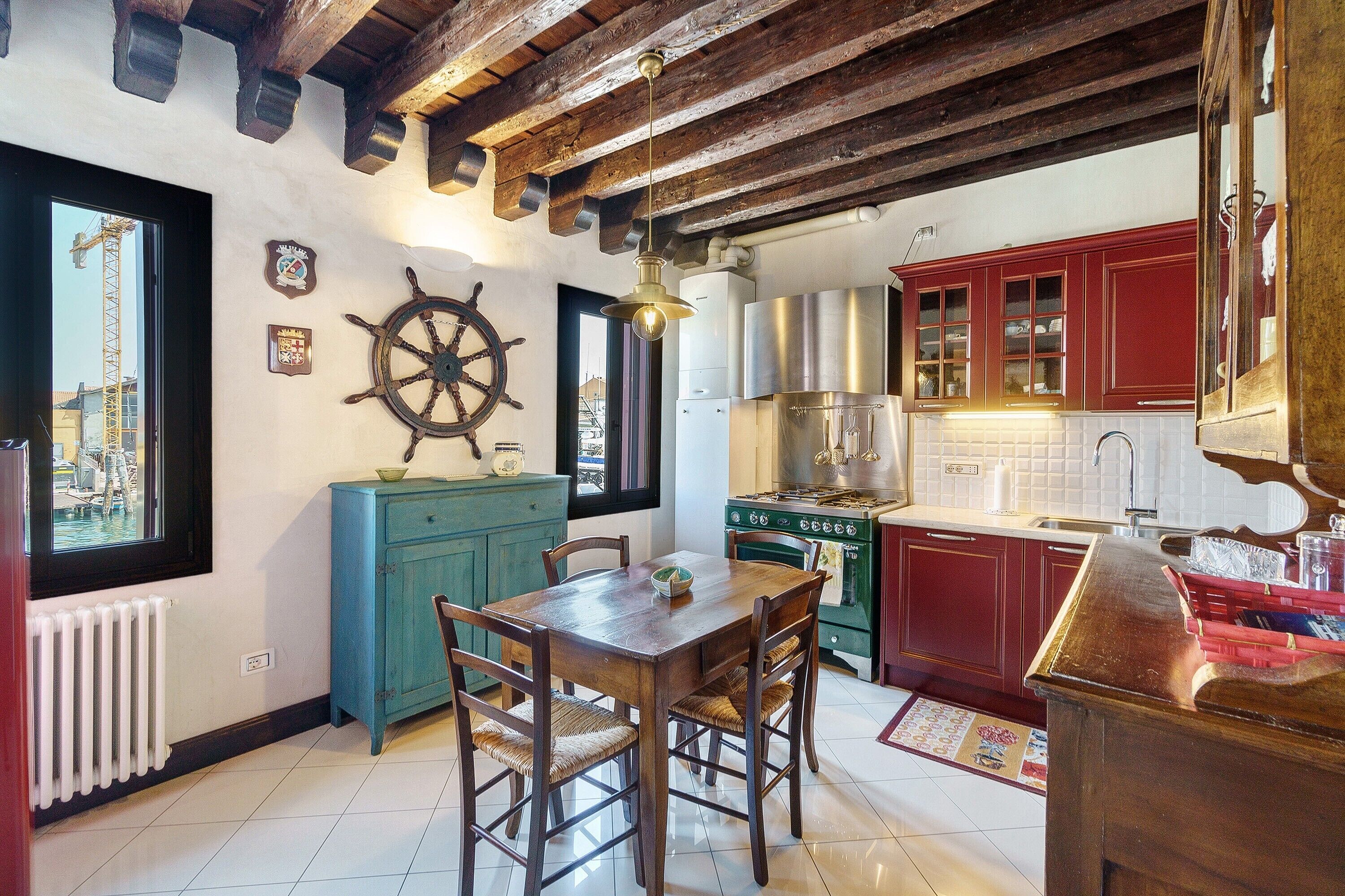 A kitchen with wooden beams, a stove, cabinets, and a dining table with chairs.