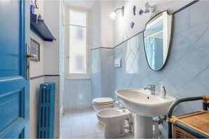A bathroom with a toilet, bidet, sink, and a mirror. - Hostdomus - Cherry Home (Alassio)