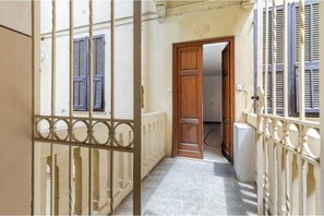 Un corridoio stretto con una porta in legno, un termosifone e un altro termosifone bianco a destra.