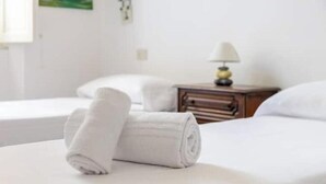 A hotel room with a neatly made bed, a bedside table with a lamp, and a wall-mounted picture. - Hostdomus - Cherry Home (Alassio)
