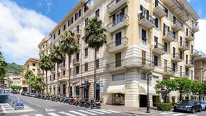 A multi-story building with balconies, parked motorcycles, and a clear sky. - Hostdomus - Cherry Home (Alassio)