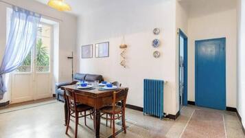 A dining area with a table set for two, a blue door, and a radiator.