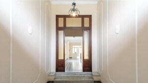 A hallway with a checkered floor, wooden doors, and a chandelier. - Hostdomus - Cherry Home (Alassio)