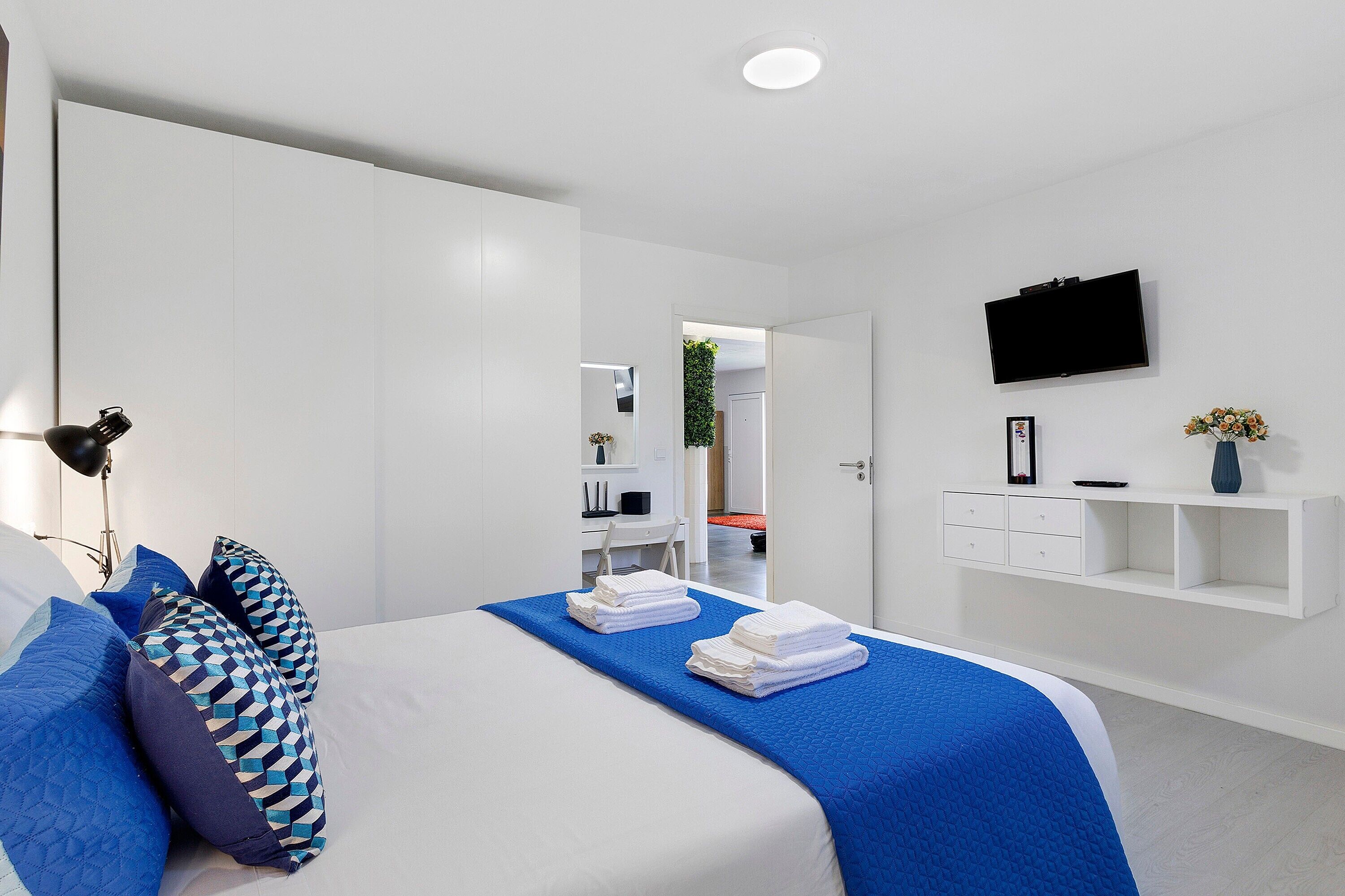 Une chambre d’hôtel moderne équipée d’un lit, d’une télévision, d’un bureau et d’une armoire.