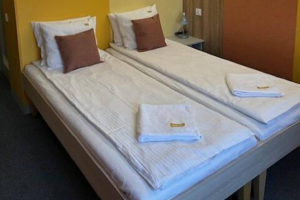 A hotel room with two beds, a control panel, and a curtain.