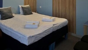 A modern hotel room with a large bed, wooden paneling on the walls, and a bedside table. - Elemels Planet (Ustroń)