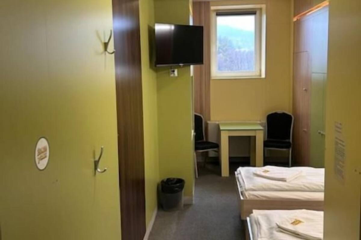 A hotel room with a bed, a desk, a chair, a television, and a window.
