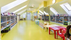A children's playroom with high ceilings, skylights, and shelves filled with toys. - Elemels Planet (Ustroń)