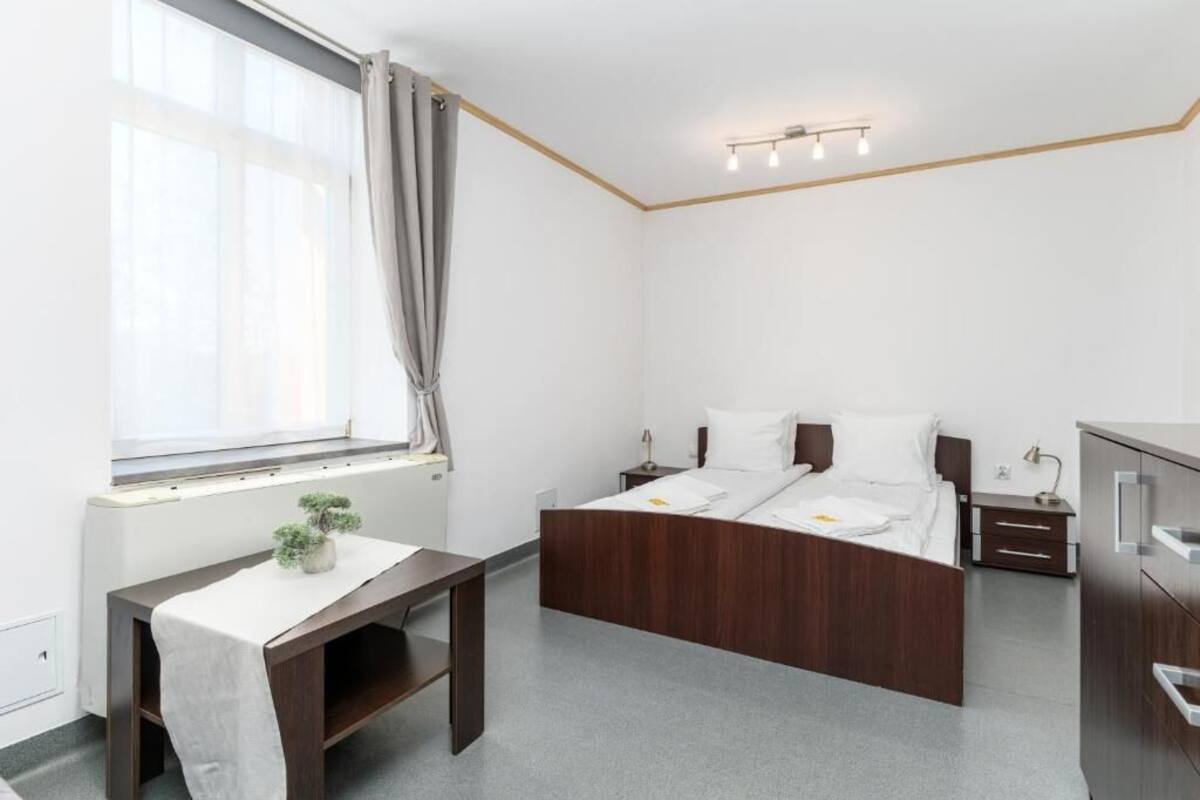 A bedroom with a bed, bedside tables, a desk, and a window with curtains.