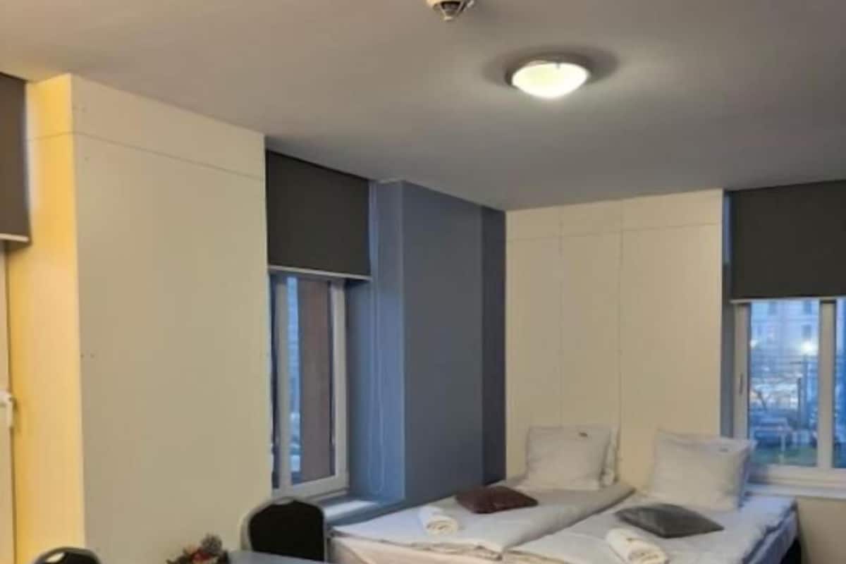 A hotel room with a bed, a desk, a chair, and a window.
