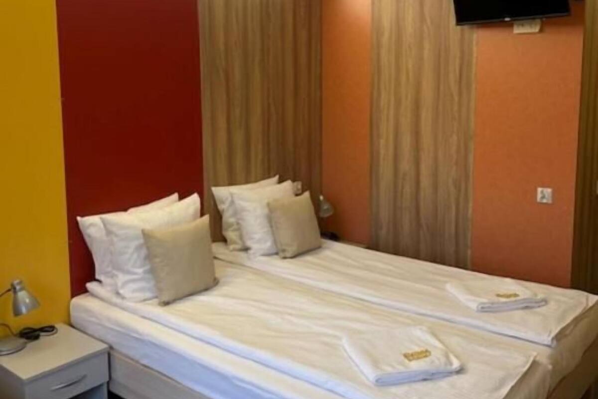 A hotel room with a bed, bedside tables, a flat-screen TV, and a ceiling light.