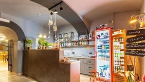 A bar area with a counter, shelves of bottles, a refrigerator, and a sign indicating a restroom. - Elemels Planet (Ustroń)