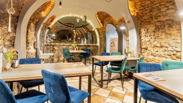 A restaurant with stone walls, wooden tables, and blue chairs. - Elemels Planet (Ustroń)