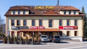 A building with multiple signs including 'SMAKI BESKIDOW,' 'APTEKA CENTRUM LEKON,' 'MAX,' and 'HOSTEL.' - Elemels Planet (Ustroń)