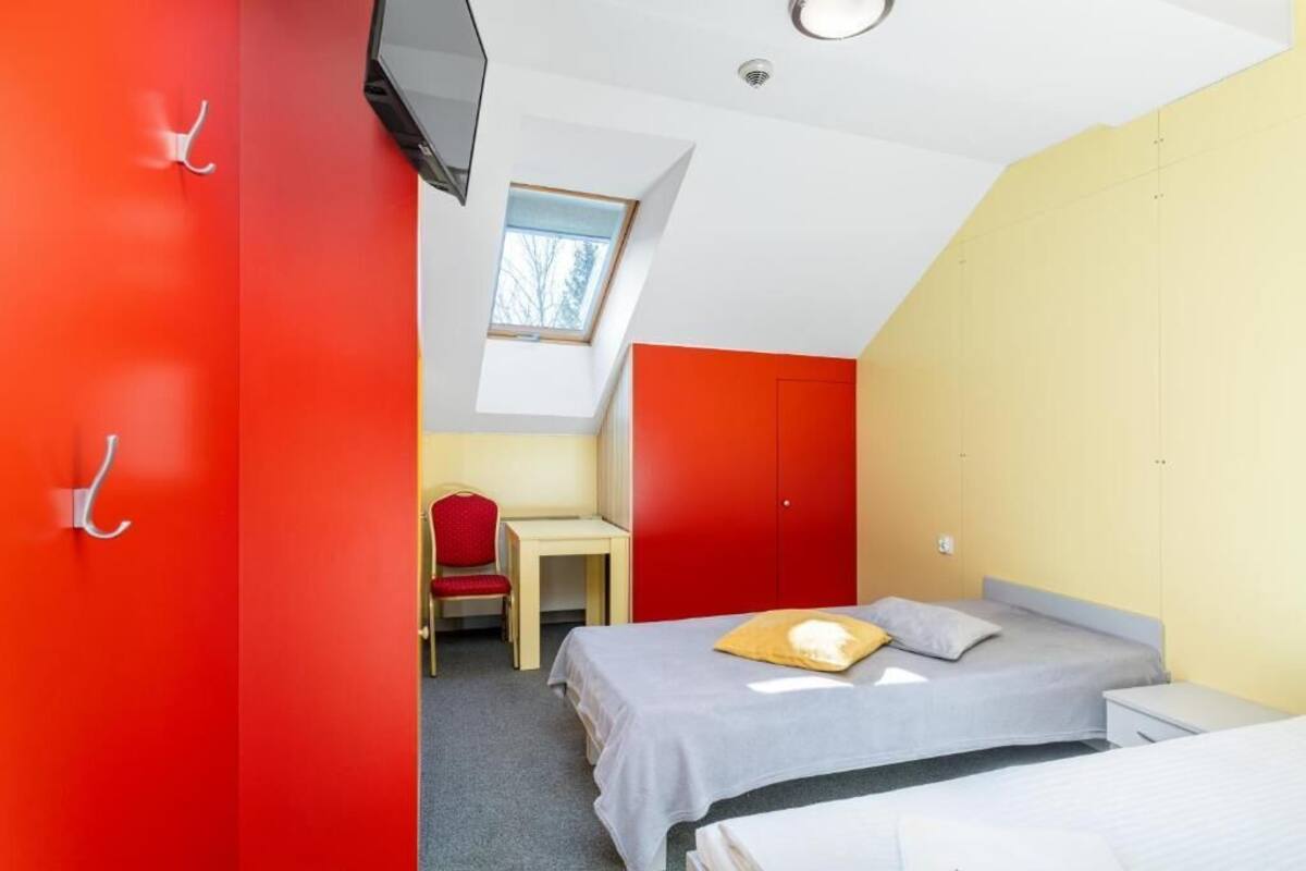 A room with two beds, a desk, a chair, and a TV.