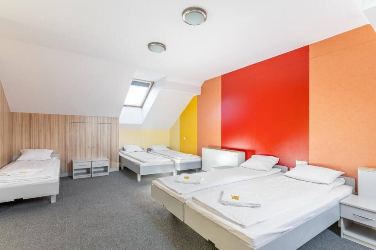 A modern hotel room with two single beds, a desk, and a small seating area.