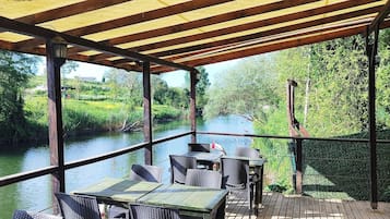 Un área de estar al aire libre cubierta con mesas y sillas, con vista al río.