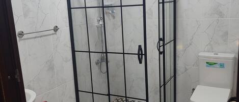 Een badkamer met een douchecabine, toilet en wastafel.