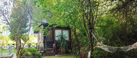 A garden with a circular pond, a small wooden structure, and a hammock.