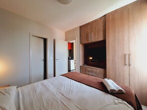 Un dormitorio con una cama, un armario y una televisión.