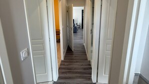Un pasillo con puertas blancas, suelo de madera e iluminación empotrada en el techo.