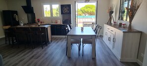 A modern kitchen with a central island, a dining table, and a view of the outdoors. - 🌴 Holiday home in Talais not far from Soulac- Terrace, small swimming pool (Talais)
