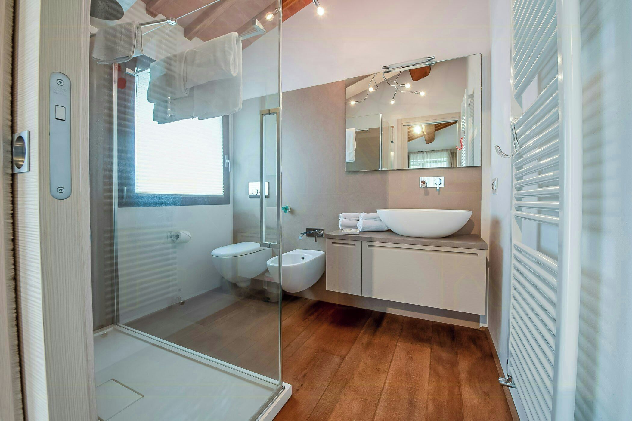 Een moderne badkamer met een glazen douchecabine, een witte wastafel en een toiletbril.