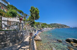 A coastal walkway with stone walls, potted plants, and a clear view of the sea. - Villa Infinity by My Villa Collection (Massa Lubrense)
