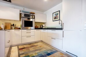 Una cocina moderna con gabinetes blancos, microondas, estufa y fregadero.