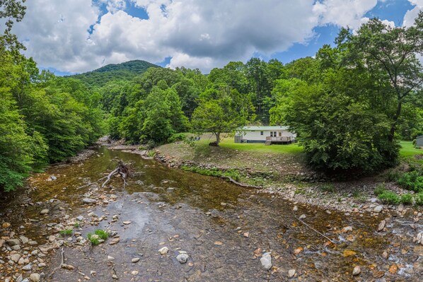 A house by a river with a grassy area and trees.