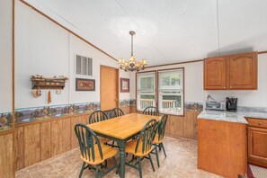 A dining area with a wooden table and chairs, a chandelier, and wooden cabinets.
