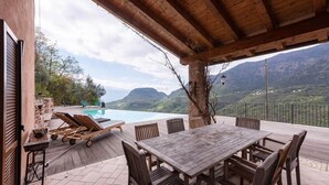 A covered outdoor area with a pool, lounge chairs, and a dining table. - Alone standing Rustico with pool, panoramic view 8 persons (Sermerio)