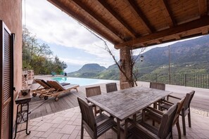 Ein überdachter Außenbereich mit Pool, Liegestühlen und einem Esstisch.