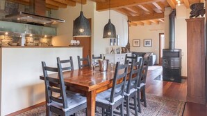 A wooden dining table with chairs, a kitchen area with a stove, and pendant lights. - Alone standing Rustico with pool, panoramic view 8 persons (Sermerio)