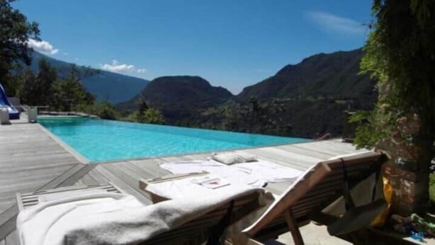 A pool with a wooden deck, lounge chairs, and a mountainous backdrop. - Alone standing Rustico with pool, panoramic view 8 persons (Sermerio)