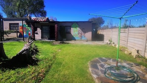 A house with a colorful mural, a stone pathway, and a green hose.