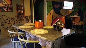 A bar area with a wooden counter, bar stools, and a television screen.