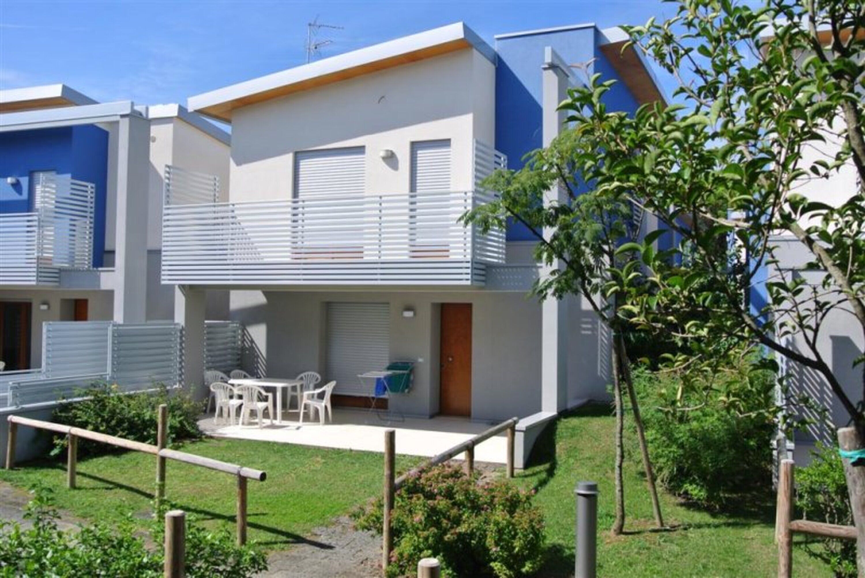 Un bâtiment moderne à deux étages, doté d’un balcon, d’un espace extérieur aménagé pour s’asseoir et d’un petit jardin.