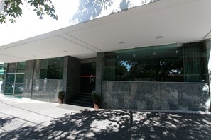 Un edifici modern amb façana de vidre, un vestíbul cobert i una escala que condueix a l'entrada.