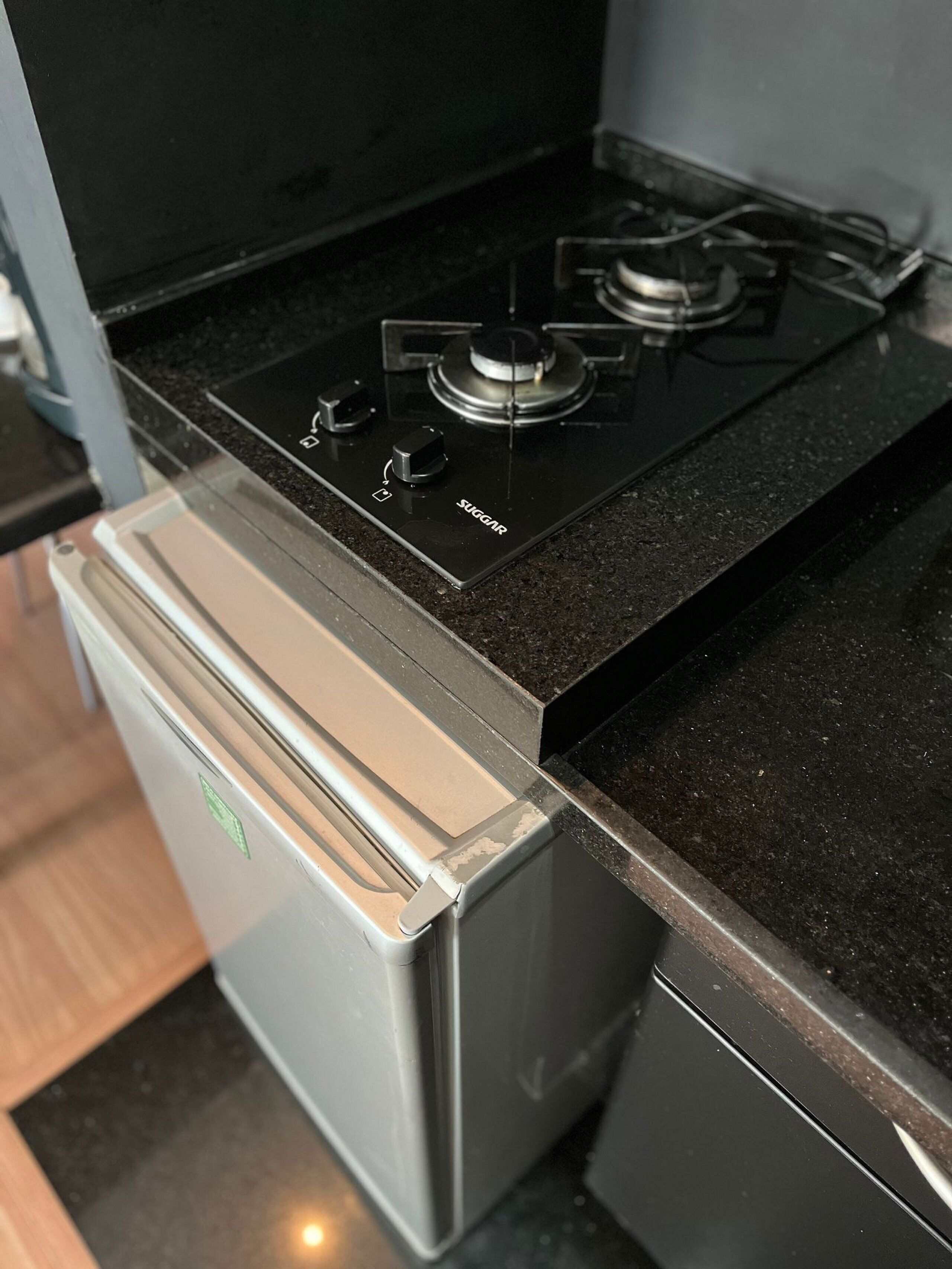 Een keuken met een zwart aanrecht, een roestvrijstalen koelkast en een gasfornuis.