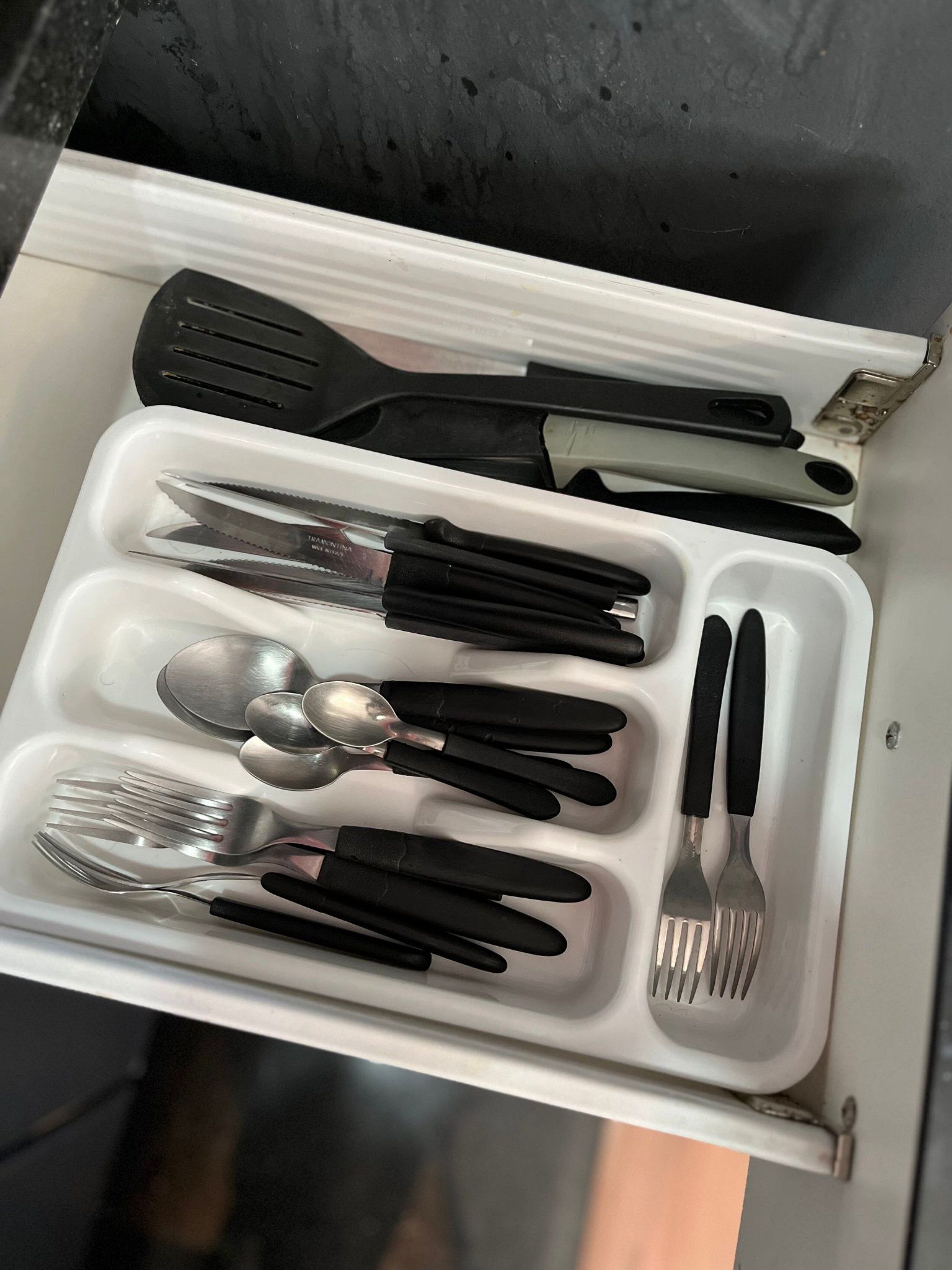 A drawer with various kitchen utensils including knives, spoons, and a spatula.