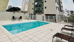 Un edificio de gran altura con piscina y asientos al aire libre.