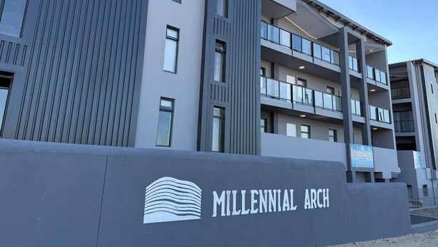 A modern multi-story building with a prominent 'Millennial Arch' sign, featuring a unique architectural design with a wave-like pattern. - Stylish Stay at 11 on Arch in Langebaan, South Africa (Langebaan)